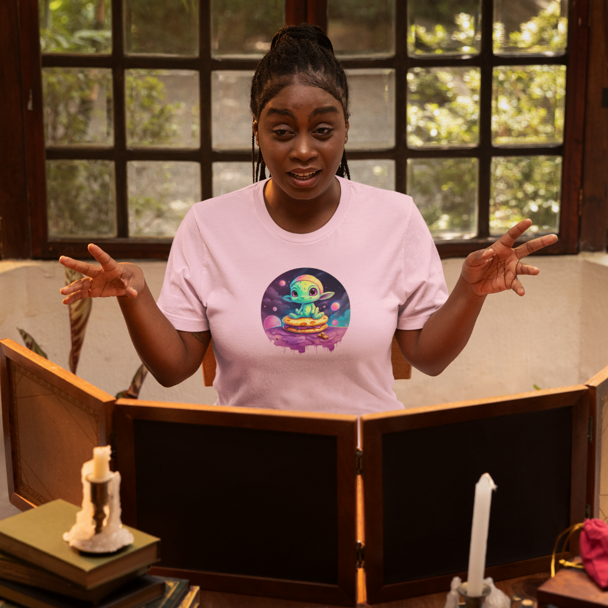 a woman tells an exciting story and wears a cool ailien print on her pink shirt.