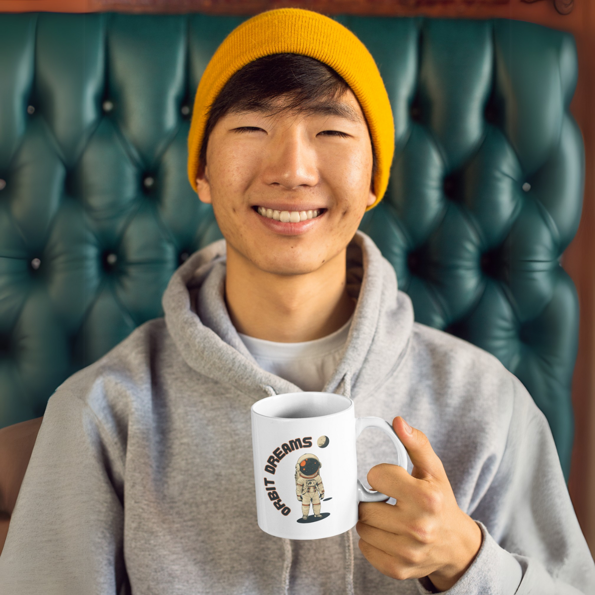 A young man grins contentedly, holding a coffe mug with an astronaut print on it.