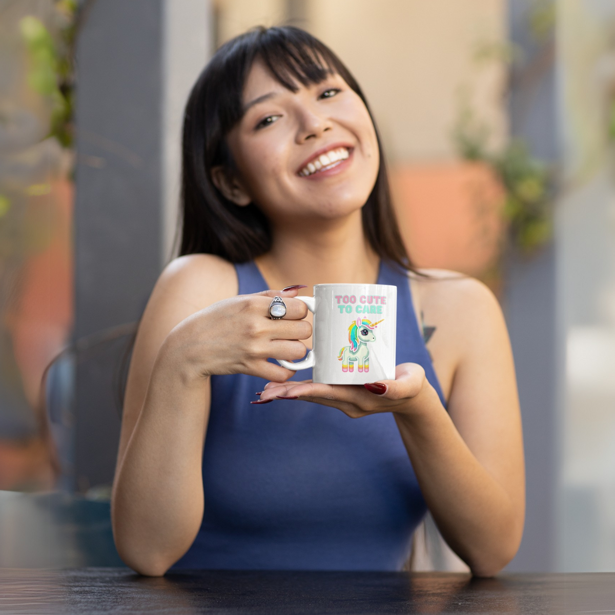 A young woman smiles friendly and holds a cup in her hand, on which a cute unicorn with a saying is depicted.